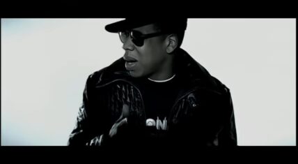 Jay-Z in the Blue Magic music video, dressed in dark attire, performing in a minimalist black-and-white setting directed by Hype Williams.