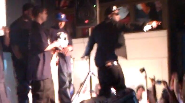 Young Jeezy performing on stage during a live concert, interacting with the audience while surrounded by his crew.