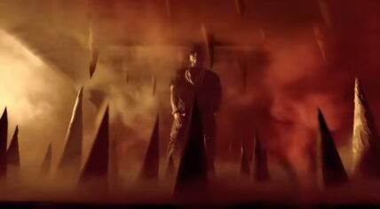 Young Jeezy in a fiery, dramatic scene from the 'Ballin' music video, surrounded by sharp spikes and intense lighting