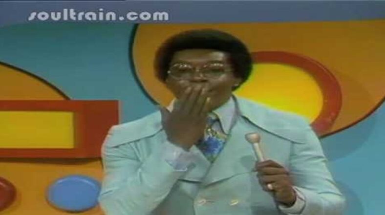 Don Cornelius, creator of Soul Train, standing in front of a Soul Train logo