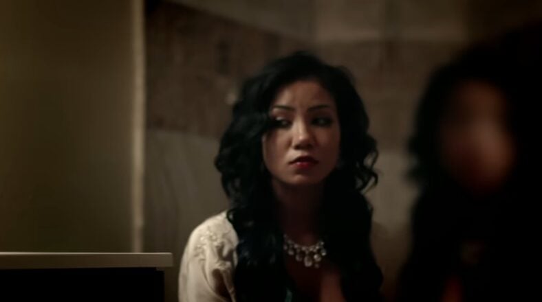 Jhené Aiko in "The Worst" music video, sitting with a pensive expression.