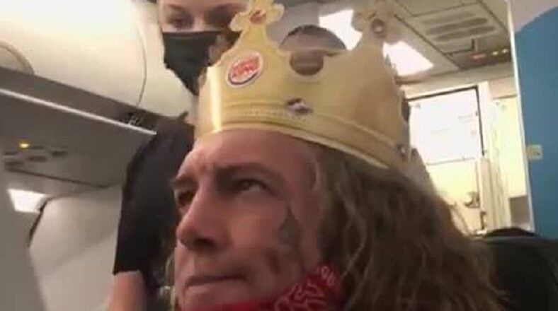 A white man, on an airplane, wearing a Burger King crown, was screaming racial slurs. The man kept screaming "n*gger b*tch," and repeatedly said "n*gger." When the flight attendant asked him to calm down, the man accused the woman of putting her stuff in his seat, and then accused her of kneeing him in the stomach.