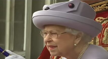Queen Elizabeth II dressed in a lavender hat and coat, attending a ceremonial event, symbolizing her role as a dedicated monarch and public figure.