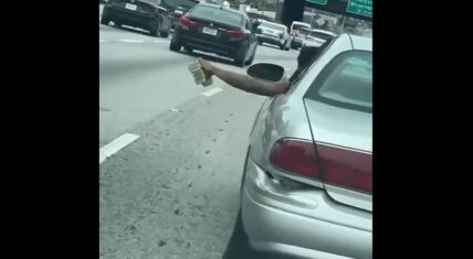 Man flaunts stacks of cash while driving down the freeway