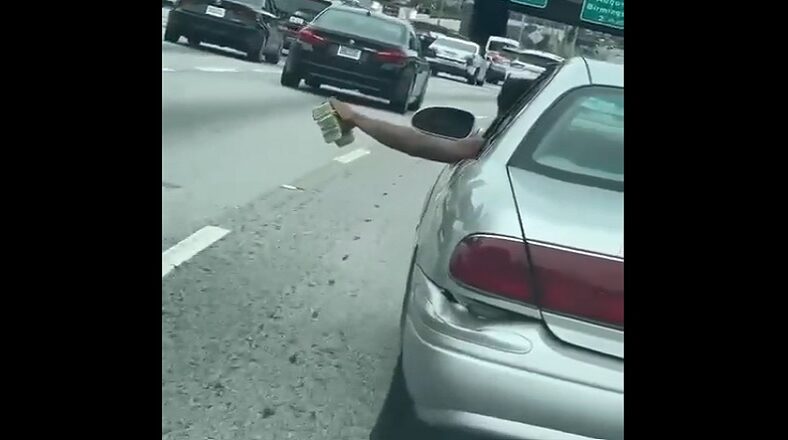 Man flaunts stacks of cash while driving down the freeway