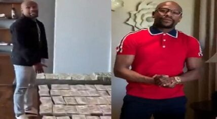 Floyd Mayweather standing next to stacks of cash and showcasing luxury watches