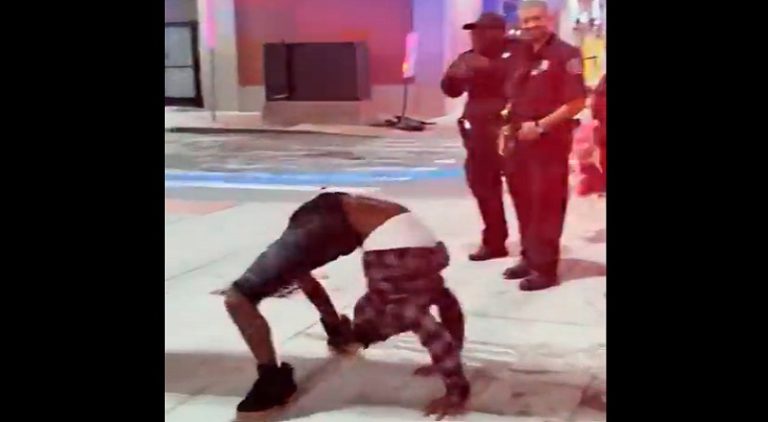 Man breakdances for the police on the side of the street
