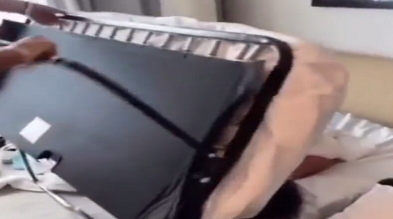 Two guys fold sleeping friend up in fold out couch and bury him