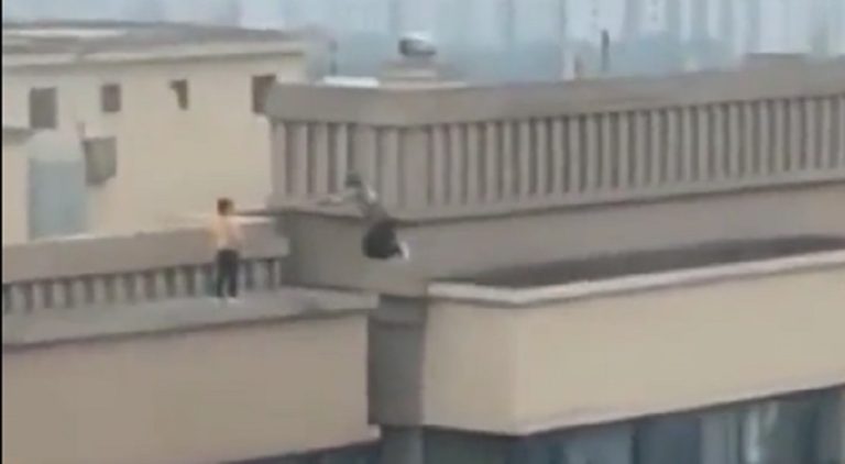 Children take turns jumping across ledges of a building