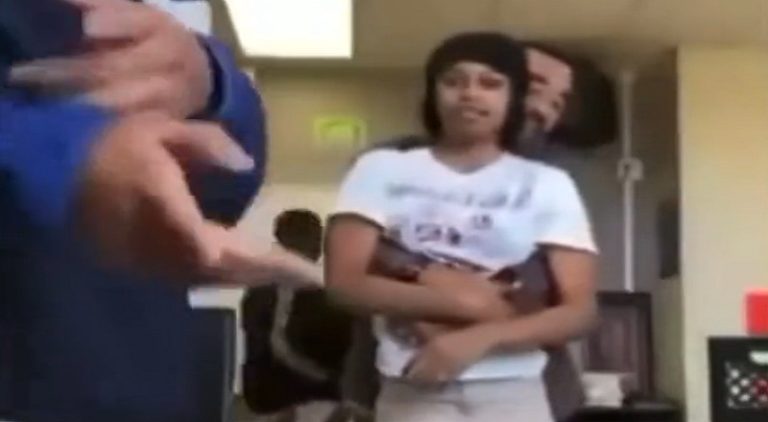 Male teacher dances with female student with arms around her