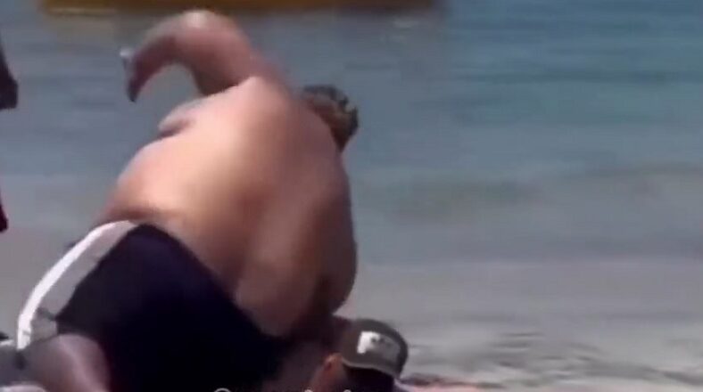 Overweight man falls on man sunbathing at the beach