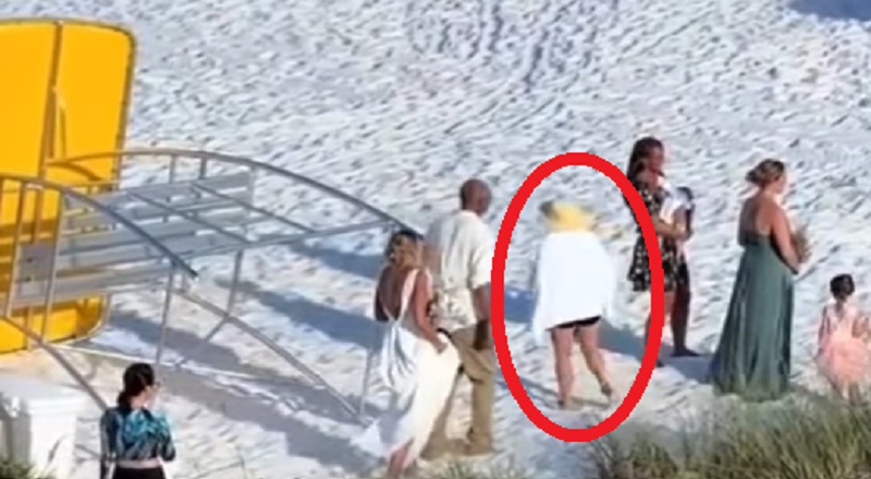 Woman walks through middle of beach wedding