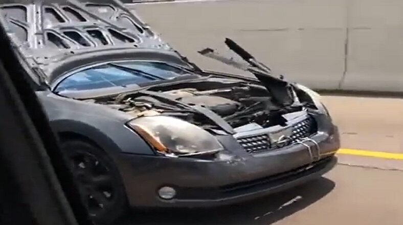 Man drives car with hood covering the windshield