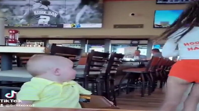 Toddler boy stops and checks out Hooters waitress