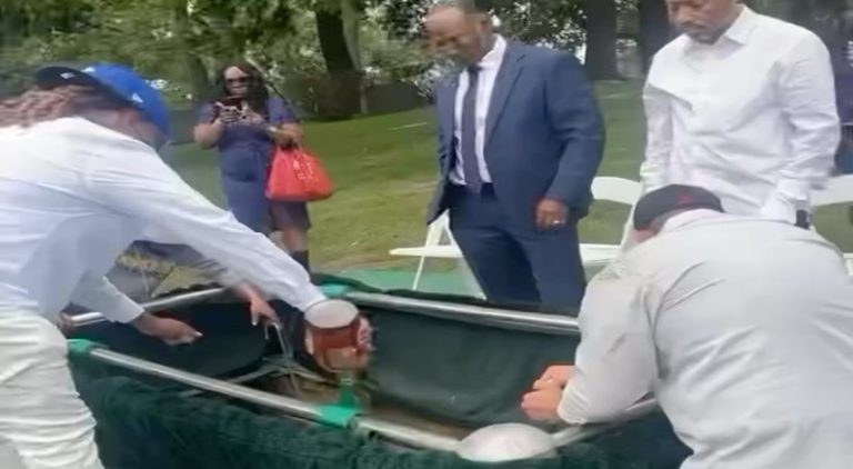 Friends pour liquor on their friend's casket during his burial