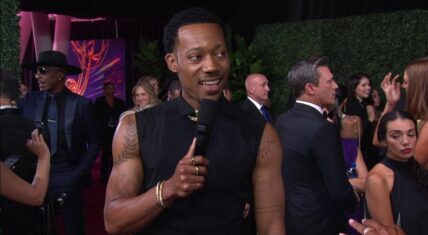 Tyler James Williams flexes muscular arms and tatts at Emmys