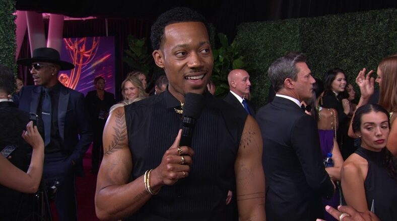 Tyler James Williams flexes muscular arms and tatts at Emmys