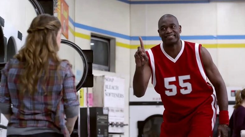 Dikembe Mutombo in a commercial, wearing a red basketball jersey with the number 55