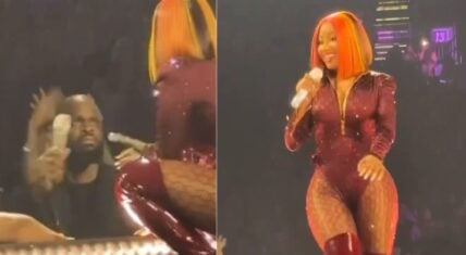 Nicki Minaj snatches microphone from security guard while smiling on stage during her concert, showing her playful side, as the guard looks confused