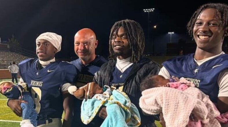 The woman’s three sons, all holding their newborns on a football field.