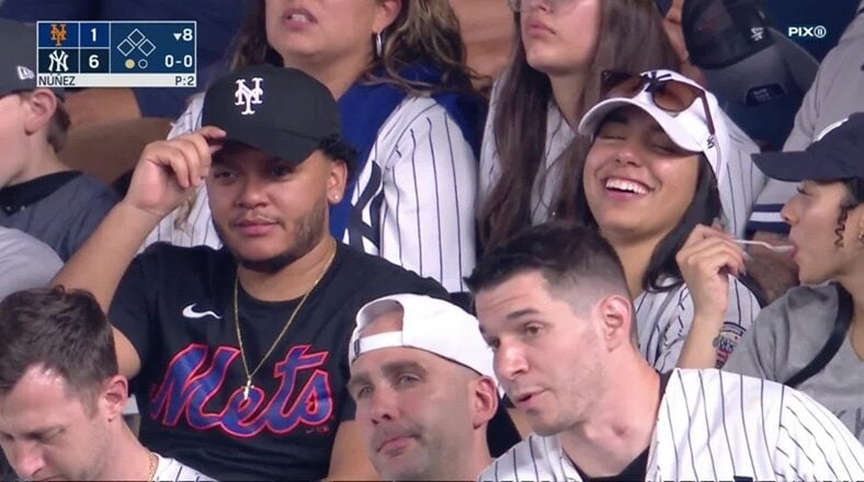 This couple took in the Mets-Yankees' game, but they are a house divided. The man is clearly a Mets fan and the woman is clearly a Yankee fan. As a result, they were having a lively conversation, as the Yankees were preparing for their win.