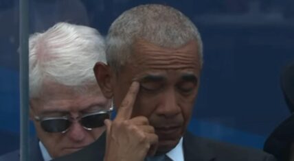 Former President Barack Obama wipes a tear from his eye with his finger during an emotional moment at the Obama Presidential Center opening, with Bill Clinton visible in the background.