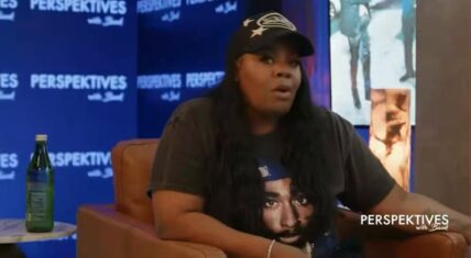 Dee Dee, longtime manager of the late rapper Lil Poppa, speaking in a studio interview on Perspektives with Bank, seated in a brown leather chair wearing a black cap and a t-shirt featuring Tupac's portrait.