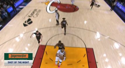 Giannis Antetokounmpo in a white Milwaukee Bucks jersey drives toward the basket for a highlight dunk against the Miami Heat in a March 2026 NBA game, captured from an overhead court view with 