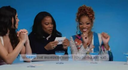 Keke Palmer smiling and gesturing while speaking during an Allure interview with her I Love Boosters co-stars, as one holds the question card "What's the weirdest thing you do to relax?"