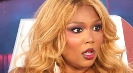 Lizzo rocks a blonde wavy hairstyle and striking red lip makeup while posing on the Scary Movie 6 red carpet.