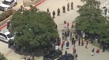 Aerial view of a large crowd gathered outside the Collin County Courthouse in McKinney, Texas, during protests following Karmelo Anthony’s guilty verdict, with sheriff’s vehicles and law enforcement officers present.