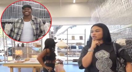 India Love stands with hand on hip in a clothing store wearing a black sports bra and leggings while her friend in a graphic t-shirt looks on with hand on chin; a smiling man in plaid shirt and cap is highlighted in a red circle in the upper left.