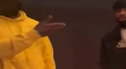 Screenshot from viral footage allegedly showing Gucci Mane in a bright yellow hoodie gesturing with his right hand while facing a bearded man in dark clothing and a chain during the reported Dallas studio confrontation.